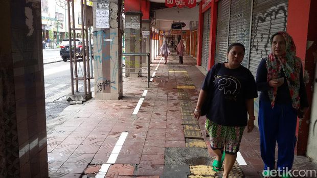 Suasana trotoar dan lorong di depan pertokoan Jalan Malioboro yang lengang. 